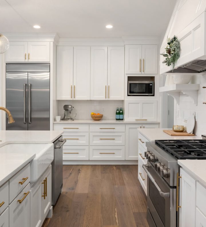 A bright kitchen with white cabinets, ceramic countertops, and stainless steel appliances.